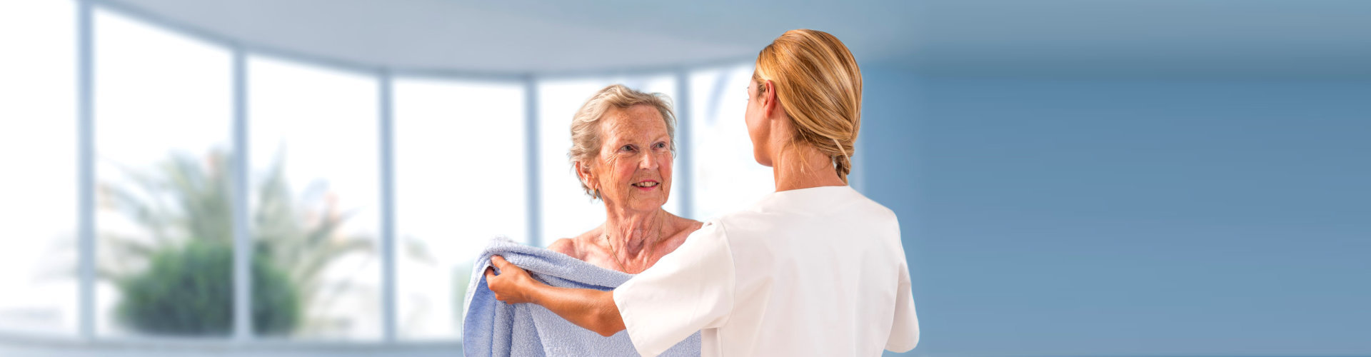 a caregiver giving a senior woman a towel