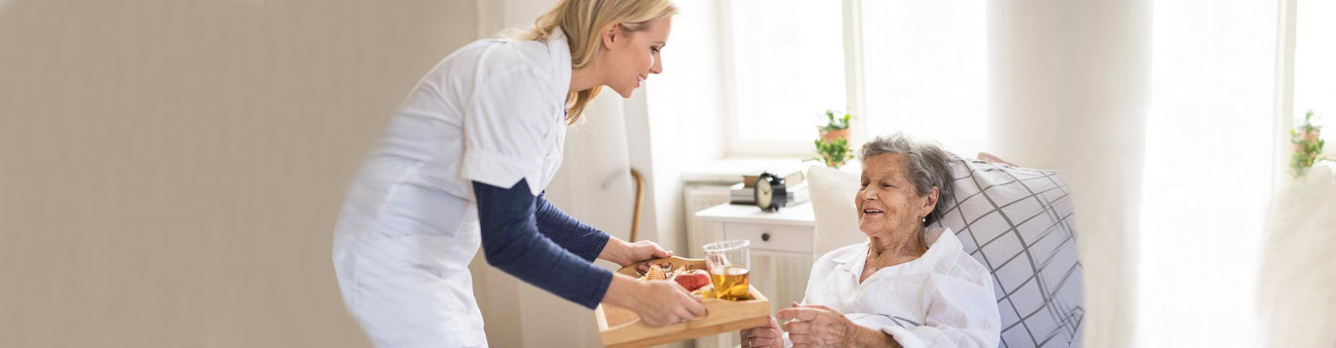 a caregiver giving meal to a senior woman in bed